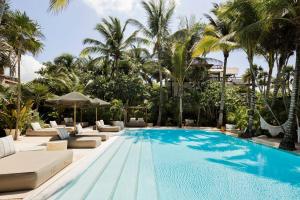 a swimming pool with lounge chairs and palm trees at Jashita Hotel in Tulum