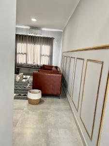 ein Wohnzimmer mit einem braunen Ledersofa in einem Zimmer in der Unterkunft Sarona LoLa E206 in Gaborone