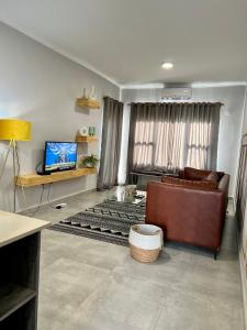 a living room with a couch and a television at Sarona LoLa E206 in Gaborone