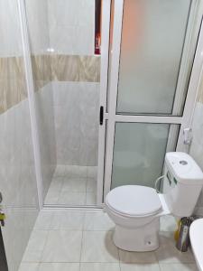a bathroom with a white toilet and a shower at Cozy Apartment in Kololo in Kampala