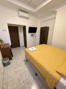um quarto com uma cama amarela e uma televisão em Hotel y Café Ixmati Suchitoto em Suchitoto