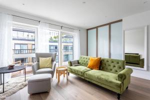 uma sala de estar com um sofá verde e uma cadeira em Modern Chelsea Apartment em Londres