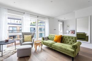 uma sala de estar com um sofá verde e duas cadeiras em Modern Chelsea Apartment em Londres