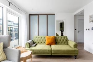 uma sala de estar com um sofá verde com uma almofada laranja em Modern Chelsea Apartment em Londres