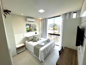 a bedroom with a bed and a large window at Hotel Recanto dos Dinossauros in Penha