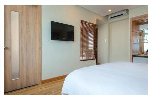 a bedroom with a bed and a television on a wall at Gemini Saigon LUXURY in Ho Chi Minh City