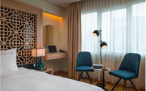 une chambre d'hôtel avec deux chaises, un lit et une fenêtre dans l'établissement Gemini Saigon LUXURY, à Hô-Chi-Minh-Ville