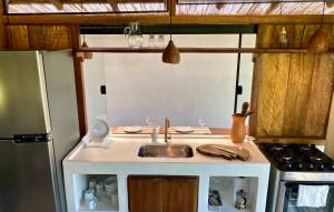 a small kitchen with a sink and a refrigerator at Casa Indigo Sargi - Bangalô, Chalé e Suite anexa in Uruçuca