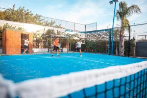 three people playing tennis on a tennis court at B&B Villa Anna in Marinella di Selinunte