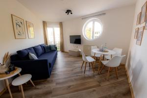 sala de estar con sofá azul, mesa y sillas en Come4Stay Passau - Wohnung Guby - 2 Zimmer I bis zu 4 Gäste, en Passau