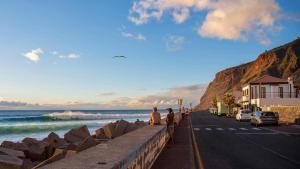 two people sitting on a wall next to the beach at Tides proprety - High tide in Paul do Mar +10 photos