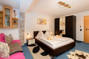 a bedroom with a large bed and a pink chair at Landhaus Josefa in Flachau