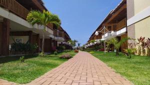 a brick path between two buildings with palm trees at Praia Itacimirim Summer Ville 19D in Itacimirim