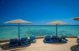 a group of chairs and umbrellas on a beach at Chalet front the beach in Hurghada