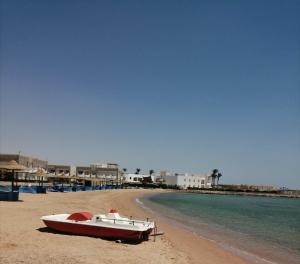 a boat sitting on a beach next to the water at Chalet front the beach in Hurghada