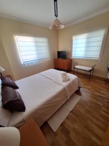 a bedroom with a large white bed and two windows at B House Verdizela in Corroios