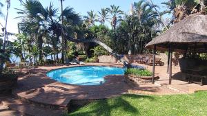 a swimming pool in a yard with palm trees at The Lagoon Flat, 53 Nkwazi Drive in Zinkwazi Beach