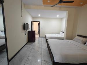 a hotel room with two beds and a tv at Comfort Cove Apartments in Mysore