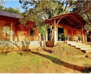 ein Backsteinhaus mit einer Veranda und einer Treppe davor in der Unterkunft Elephant Arcade in Tissamaharama
