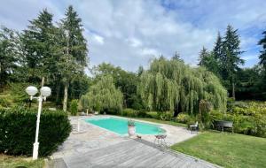 a swimming pool in a garden with a table and chairs at Le moulin de la Vernoelle in Prémilhat