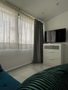 Luxury bungalow Maspalomas Gran Canaria في ماسبالوماس: غرفة نوم بسرير وتلفزيون بشاشة مسطحة