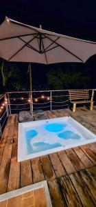 a swimming pool on a deck with an umbrella at Glamping Reserva del Roble in La Vega