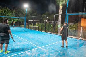 two men playing tennis on a tennis court at night at B&B Villa Anna in Marinella di Selinunte