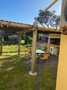 una mesa de picnic y sillas bajo una pérgola de madera en Medanos del Portal, en Piriápolis