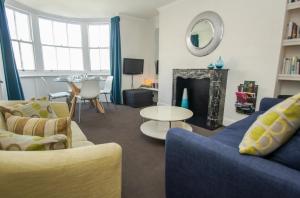 een woonkamer met een blauwe bank en een open haard bij New Steine Apartment - Sea View - by Brighton Holiday Lets in Brighton & Hove