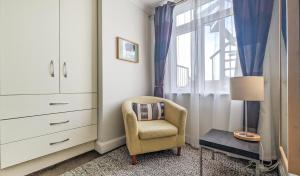 een slaapkamer met een stoel, een dressoir en een raam bij New Steine Apartment - Sea View - by Brighton Holiday Lets in Brighton & Hove