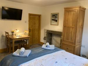a bedroom with a bed and a table and a television at The Wharfe at Greystones - Cosy, comfortable retreat in Buckden