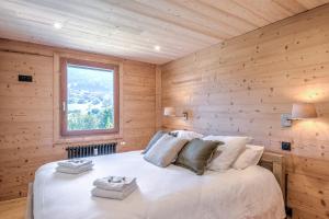 - une chambre avec un lit et un mur en bois dans l'établissement Appartement Chablis - Welkeys, à Combloux