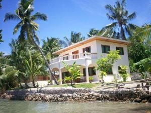 a large white house with palm trees and water at Mangrove Inn 