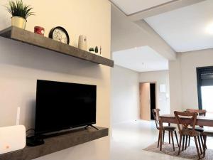 uma sala de estar com uma televisão e uma mesa com cadeiras em Appartement cosy proche Aéroport em Deroua