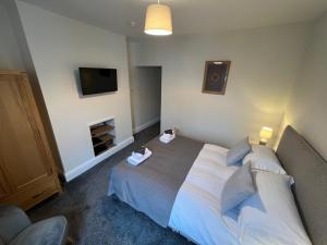 a bedroom with a bed and a flat screen tv at Dolly Waggon Guest House in Keswick