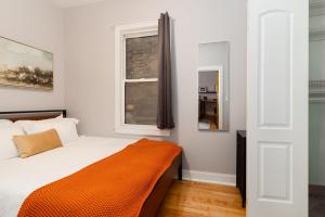 um quarto com uma cama com um cobertor laranja em Flexhome Logan Square 1BR Apt B1 - READ INFO em Chicago