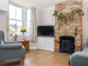a living room with a brick fireplace and a tv at 46 By The Creek in Faversham