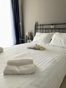a white bed with two folded towels on it at WINDSOR PLACE APARTMENT - VOULIAGMENI in Athens