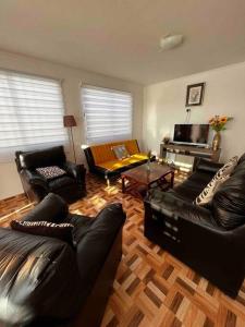 sala de estar con muebles de cuero negro y suelo de madera. en Casa 10 personas cerca de Bahia Inglesa, en Caldera