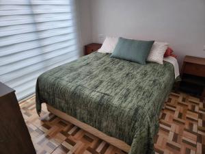 a bedroom with a bed with a green blanket and pillows at Casa 10 personas cerca de Bahia Inglesa in Caldera