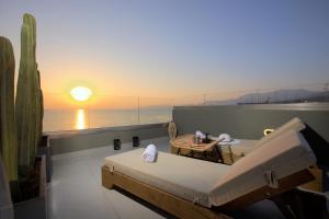 een bed en een tafel in een kamer met zonsondergang bij Hersonissos Beach Front Suites in Chersonissos