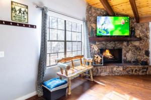 a living room with a stone fireplace and a tv at Winter Getaway Spa Fire-table Close to slopes in Big Bear Lake