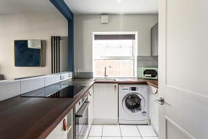 a kitchen with a washing machine and a window at Beautiful Aldgate Apartment in London