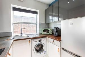 a kitchen with a washing machine and a microwave at Beautiful Aldgate Apartment in London