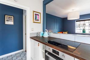a kitchen with blue walls and a counter top at Beautiful Aldgate Apartment in London