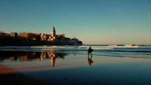 uma pessoa caminhando na praia perto do oceano em Emilio Tuya 60 em Gijón