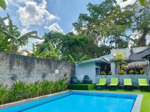 a swimming pool in the backyard of a house with green chairs at The Jungle Hostel Canggu in Canggu