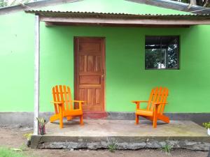 dos sillas naranjas sentadas fuera de una casa verde en Cabañas piedra grande ometepe, en Altagracia