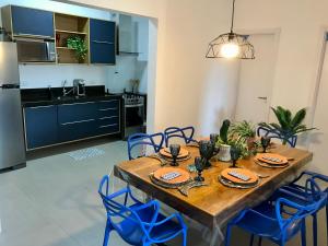 uma cozinha e sala de jantar com uma mesa de madeira e cadeiras azuis em Ubatuba Apto Encantador em Ubatuba