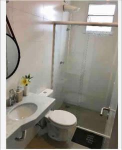 a bathroom with a toilet and a sink and a mirror at Ubatuba Apto Encantador in Ubatuba